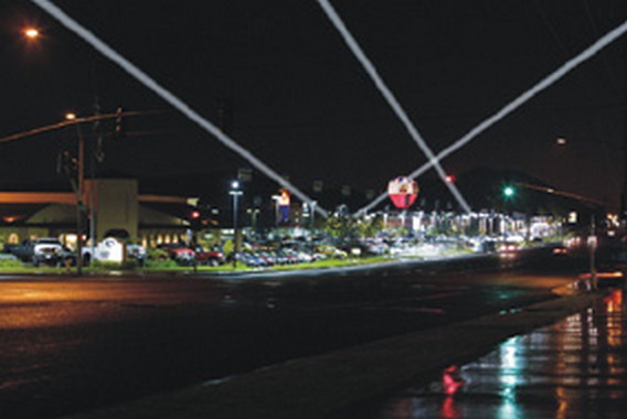 Advertising searchlight rental: beams over a car dealership lot at night